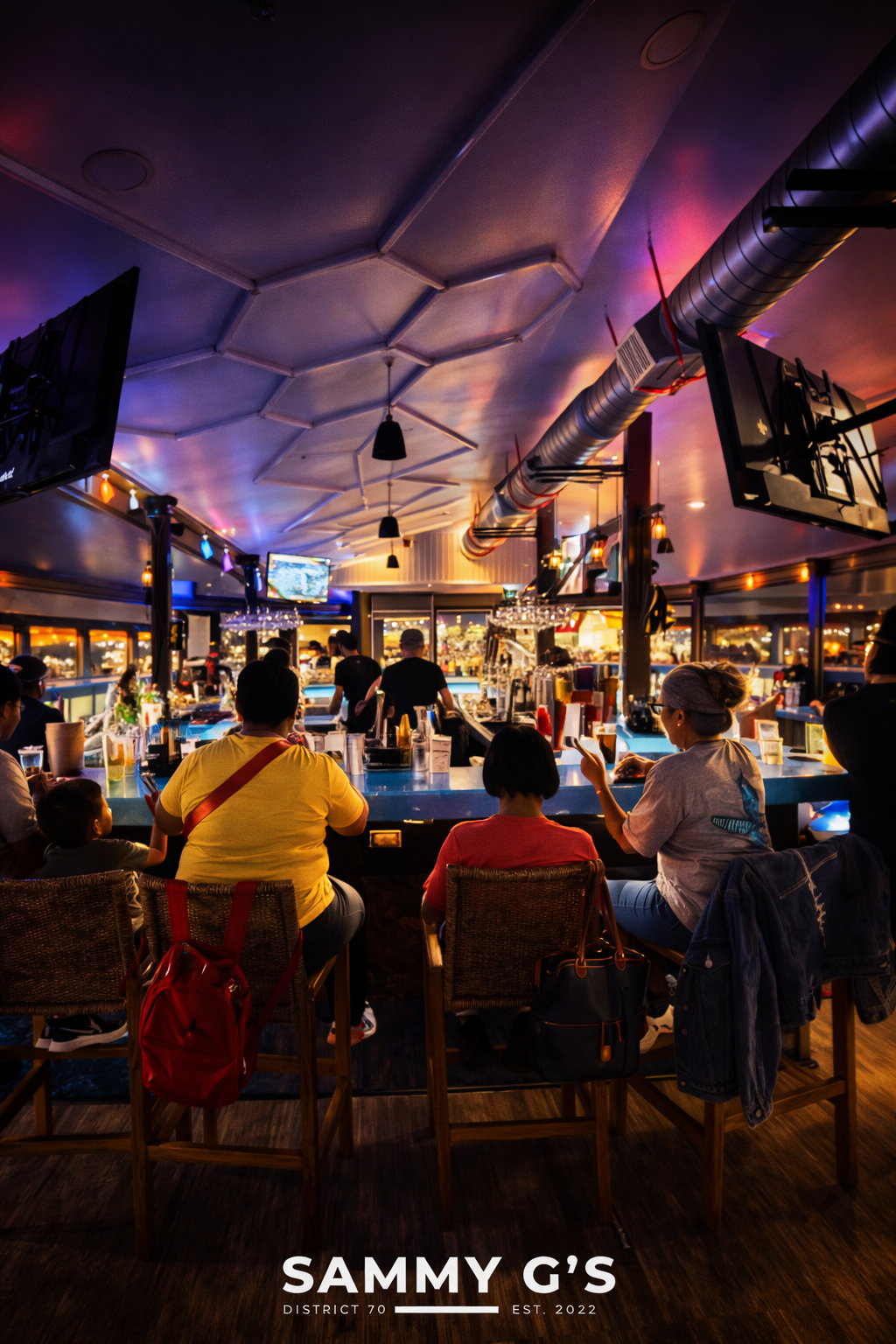 Guests seated at Sammy G's upstairs bar with colorful lighting